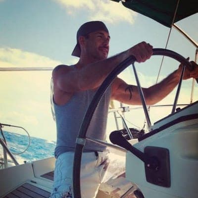 Justin Cateron at the wheel of a sailboat on open water